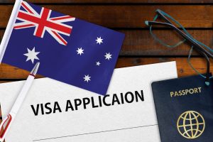 An Australian flag, passport, glasses, and visa application form on a wooden table, highlighting the process of applying for a 101 visa.