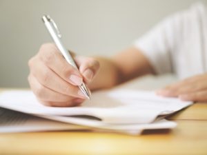 Person filling out a form with a pen, representing the process of applying for a Bridging Visa B