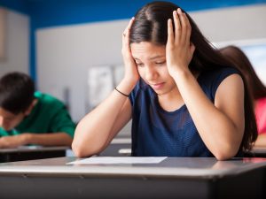 Stressed student sitting at a desk during an exam, representing challenges of the citizenship test in Australia.