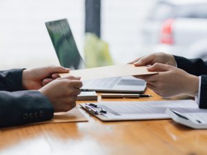 Two people exchanging documents over a desk, representing the process of family migration to Australia and visa applications.