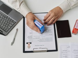 Application for parent visa Australia being stamped 'Approved' on a desk with a laptop, pen, and documents.