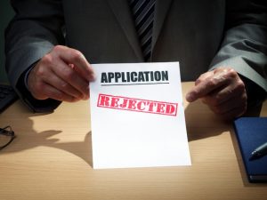 a man holding a paper with the word application rejected indicating rejected translation