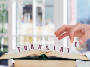 a man arranging a alphabeth blocks with the word translate on the top of a book