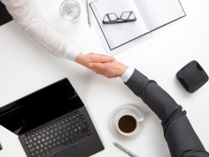 Business handshake at a desk symbolising guidance in navigating health insurance for work visa requirements.